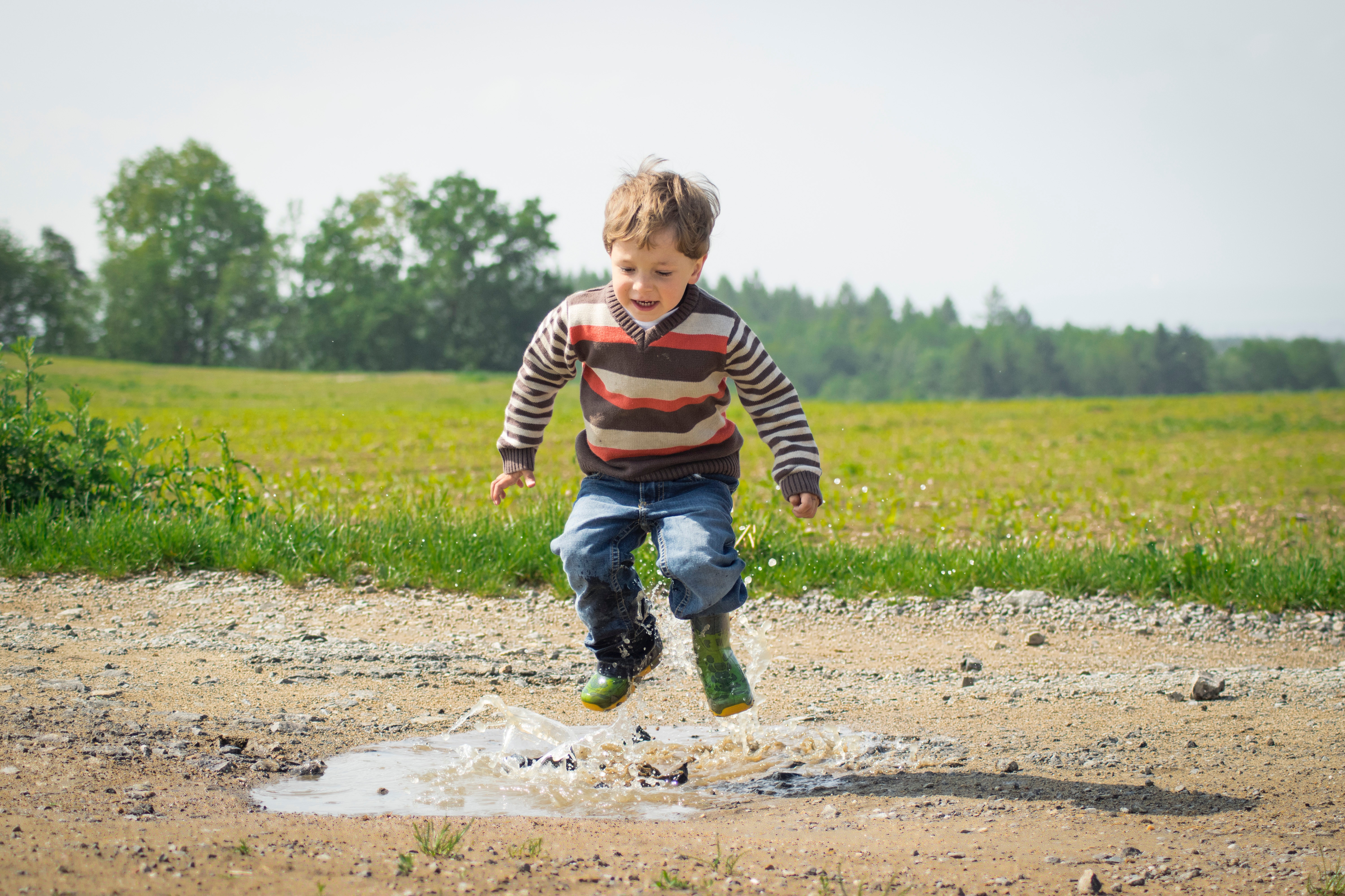 Photo of a child hopping in a puddle.